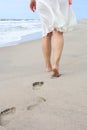 Beach trip - a woman walks along a sandy beach in a relaxed way, leaving footprints in the sand. Close-up of women& x27;s Royalty Free Stock Photo