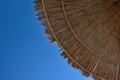 Beach umbrella, awning, canopy made of straw and reeds against a clear blue sky, on the beach on a sunny day Royalty Free Stock Photo