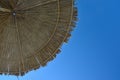 Beach umbrella, awning, canopy made of straw and reeds against a clear blue sky, on the beach on a sunny day Royalty Free Stock Photo