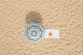 Beach umbrella near towel and other vacationist`s stuff on sand, aerial view Royalty Free Stock Photo