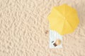 Beach umbrella near towel and other vacationist`s stuff on sand, aerial view. Space for text Royalty Free Stock Photo