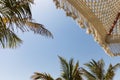 Beach umbrella and palm trees on the background of blue sky Royalty Free Stock Photo