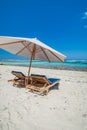 Beach umbrella on the sand with sun lounger chairs.