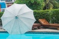 Beach umbrella with wooden seat at pool side in hotel Royalty Free Stock Photo