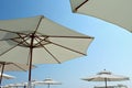 Beach umbrellas, large, white against the blue sky.