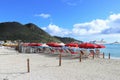 Philipsburg, St. Martin - 1/23/18: Beach umbrellas and lounge chairs along the beach and the Carnival Conquest cruise ship docked Royalty Free Stock Photo