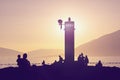 Beach vacation concept. Mediterranean landscape with silhouettes of lighthouse and tourists at sunset. Montenegro