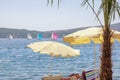 Beach vacation concepts. Beach umbrellas on coast, colorful sailboats on water. Montenegro