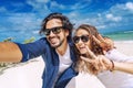 Beach vacation couple taking selfie photograph using smartphone relaxing and having fun holding smart phone camera. Young Royalty Free Stock Photo