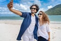 Beach vacation couple taking selfie photograph using smartphone relaxing and having fun holding smart phone camera. Young Royalty Free Stock Photo