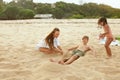 Beach Vacation. Family Enjoying Summertime At Tropical Resort. Mother And Little Girl Burying Boy In Sand.