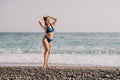 A tourist woman in blue bikini on beach enjoys the turquoise sea during her summer holiday. Rear view. Beach vacation Royalty Free Stock Photo