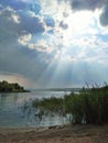 Beach with vegetation consecrated to the sun`s rays coming through the clouds