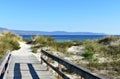 Beach with vegetation in sand dunes and wooden boarwalk with fence. Blue sea, clear sky, sunny day. Galicia, Spain. Royalty Free Stock Photo