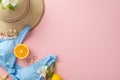 Beach vibes! Top view flat lay of blue swimsuit with sunhat, earrings, bracelet, and flowers orange fruit on pastel pink Royalty Free Stock Photo