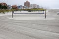 Beach volleyball net on a deserted recently raked beach sand court near thee ocean on an overcast day