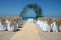 Beach wedding with chairs, palm arch and ocean in background