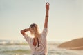 The beach is where I feel the most free. Rearview shot of a young woman on the beach with her hand in the air. Royalty Free Stock Photo