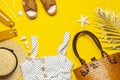 Beach wicker straw or rattan women`s eco bag, white dress straw hat sandals golden tropical leaf on yellow background Flat lay to Royalty Free Stock Photo