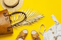 Beach wicker straw or rattan women`s eco bag, white dress straw hat sandals golden tropical leaf on yellow background Flat lay to Royalty Free Stock Photo