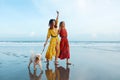 Beach. Women With Dog On Sandy Coast. Fashion Girls In Bohemian Clothing Walking Barefoot With Pet