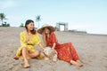 Beach. Women With Dog Sitting On Sandy Coast. Fashion Girls In Bohemian Clothing With Straw Hat Enjoying Resting