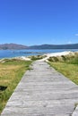 Beach with wooden boardwalk, sand dunes, mountain and bay with turquoise water and blue sky. Carnota, Spain.