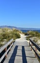 Beach with wooden boardwalk, vegetation in sand dunes and mountain. Blue sea, clear sky, Galicia, Spain. Royalty Free Stock Photo