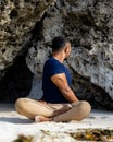 Beach yoga. Asian man practicing Parivrtta Sukhasana outdoor. Sitting in variation of Lotus pose. Easy twist pose. Stretching hips Royalty Free Stock Photo