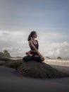 Beach yoga. Asian woman practicing Parivrtta Sukhasana outdoor. Sitting in variation of Lotus pose. Easy twist pose. Stretching Royalty Free Stock Photo