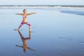 Beach yoga. Caucasian woman practicing Virabhadrasana II, Warrior II Pose. Strong body. Healthy lifestyle. Water reflection. Yoga Royalty Free Stock Photo