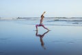 Beach yoga. Slim Caucasian woman practicing Virabhadrasana II, Warrior II Pose. Strong body. Healthy lifestyle. Water reflection. Royalty Free Stock Photo