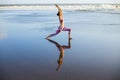 Beach yoga. Slim Caucasian woman practicing Virabhadrasana II, Warrior II Pose. Strong body. Healthy lifestyle. Water reflection. Royalty Free Stock Photo