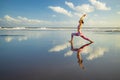 Beach yoga. Slim Caucasian woman practicing Virabhadrasana II, Warrior II Pose. Strong body. Healthy lifestyle. Water reflection. Royalty Free Stock Photo