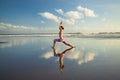 Beach yoga. Slim Caucasian woman practicing Virabhadrasana II, Warrior II Pose. Strong body. Healthy lifestyle. Water reflection. Royalty Free Stock Photo