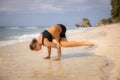 Beach yoga. Strong Caucasian woman practicing Eka Pada Bakasana, One-Legged Crow Pose. Arm balance and concentration. Yoga retreat