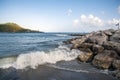 Stones of the breakwater and the inletâs foreland with the old watchtower. Marina di Camerota, Italy. Royalty Free Stock Photo