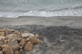 beachfront view with beach waves and fine black sand and brown rocks