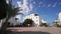 Beachfront villas on sunny day, palm trees line approach, clear blue sky, luxury holiday homes investment