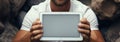 Beachgoer in white shirt lies on sand, holding tablet with blank screen