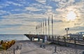 Beachlife early in the morning with pier, sand, rising sun, beach chairs and blue sky on the island Ruegen