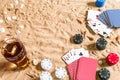 Beachpoker. Chips and cards on the sand. Around the seashells and cold drink in a glass. Top view Royalty Free Stock Photo