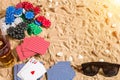 Beachpoker. Chips and cards on the sand. Around the seashells, sunglasses and cold drink in a glass. Top view Royalty Free Stock Photo