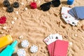 Beachpoker. Chips and cards on the sand. Around the seashells, sunglasses and suntan cream. Top view Royalty Free Stock Photo