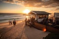 beachside eatery, with view of the sun setting over the ocean, and people walking or swimming in the background