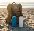 Beachside Essentials: Tan Backpack with Water Flasks by the Shore Royalty Free Stock Photo