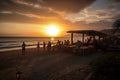 beachside restaurant, with beautiful sunset in the background, and waitstaff bringing last orders of the day Royalty Free Stock Photo