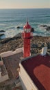 Beacon rising rocky shore sunny summer day aerial view. Red lighthouse on coast Royalty Free Stock Photo