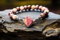 beaded bracelet with a silver charm resting on a marbled stone