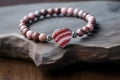 beaded bracelet with a silver charm resting on a marbled stone